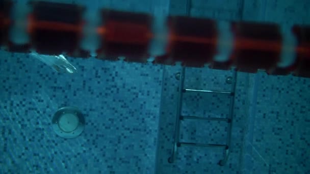 Спортсмен ныряет под воду в бассейн с голубой водой. Сверхмедленное движение - Кадры, видео