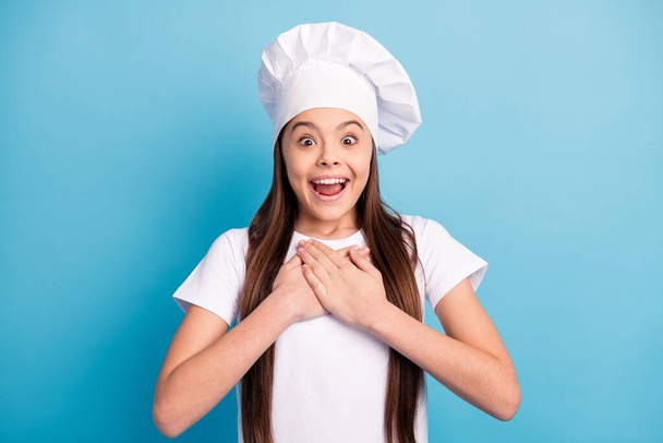 Photo of amazed astonished happy small lady hold hands chest gift wear hat chef isolated on blue color background - Fotografie, Obrázek