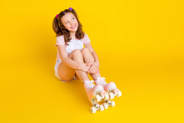 Full length photo of schoolgirl wearing rollers sit floor look empty space isolated bright yellow color background - Foto, Imagem