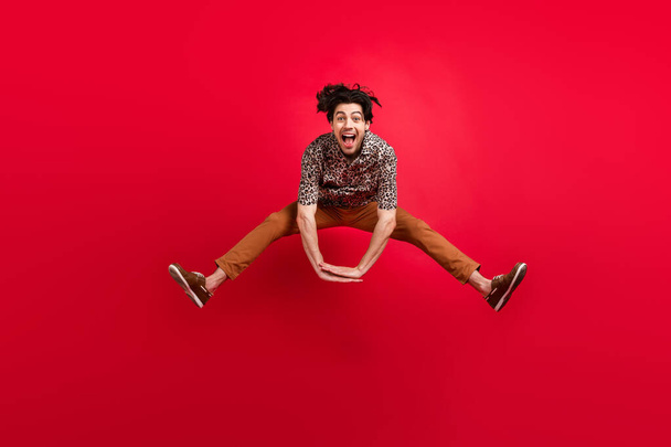 Фотографія повного розміру усміхненого недбалого веселого чоловіка, що стрибає активний енергійний хороший настрій ізольовано на червоному тлі
 - Фото, зображення