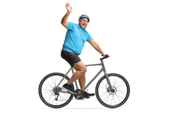 Cheerful mature male cyclist riding a road bike and waving isolated on white background - Φωτογραφία, εικόνα