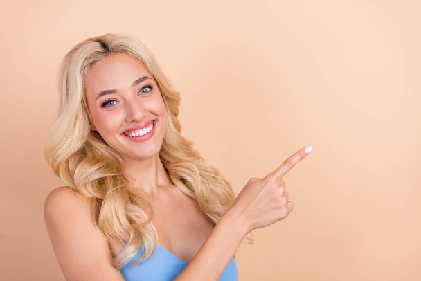 Photo of cute adorable young lady wear blue singlet smiling pointing finger empty space isolated beige color background - Φωτογραφία, εικόνα