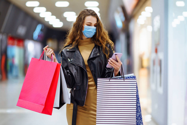 Κομψή γυναίκα με προστατευτική μάσκα μετά τα ψώνια. Μαύρη Παρασκευή. Καταναλωτισμός, αγορές, πώληση, τρόπος ζωής, τουριστική έννοια. - Φωτογραφία, εικόνα