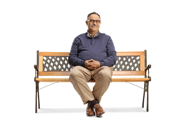 Smiling mature man with glasses sitting on a bench isolated on white background - Foto, Bild