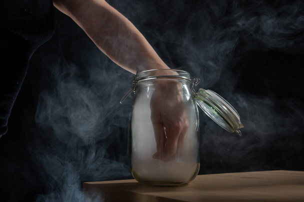 Woman takes out fog from a glass jar. - Photo, Image
