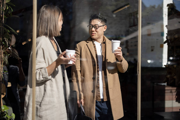 Beyaz erkek ve beyaz kadın gider, konuşur ve kahve içer. - Fotoğraf, Görsel