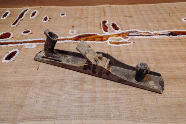 Old metallic jointer plane laying on wood table. Woodworking tools on wooden table. Carpentry workshop - Photo, Image