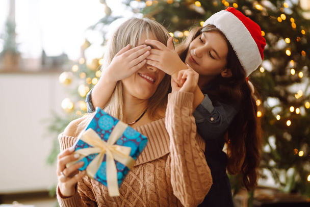 Happy mom and her cute daughter girl exchanging gifts. Merry Christmas and Happy Holidays. - 写真・画像