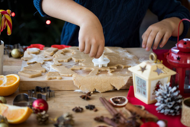 Little cute boy zrobić świąteczne pierniki ciasteczka w kuchni noworocznej. - Zdjęcie, obraz