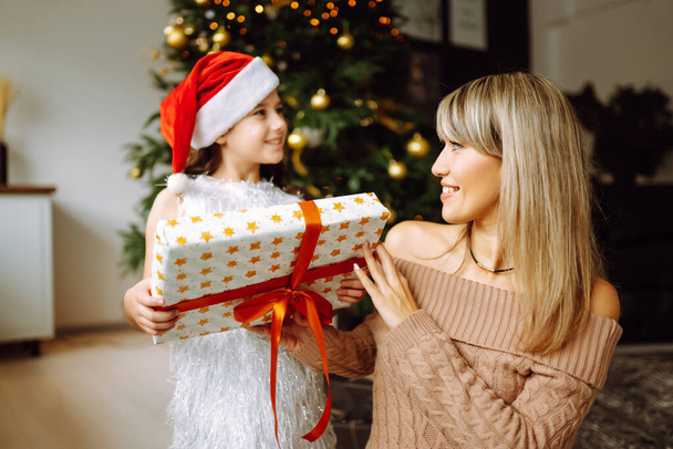 Happy mom and her cute daughter girl exchanging gifts. Merry Christmas and Happy Holidays. - Foto, immagini