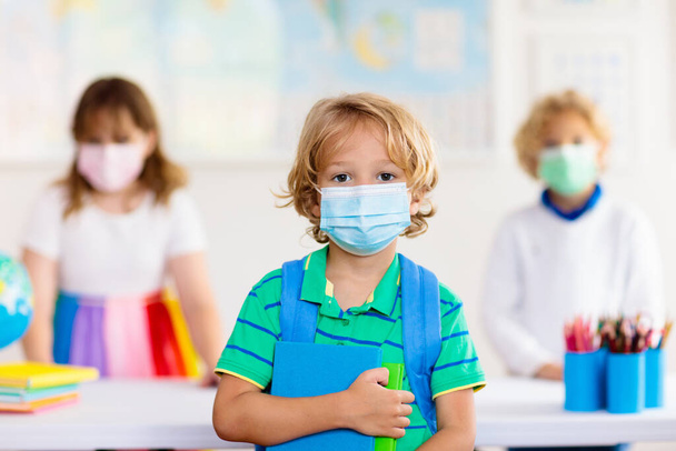 コロナウイルスやインフルエンザの流行の間に顔マスクを身に着けている学校の子供。男の子と女の子は、 covid-19の隔離とロックダウンの後に学校に戻ります。コロナウイルスの予防のためのマスクの子供のグループ.  - 写真・画像
