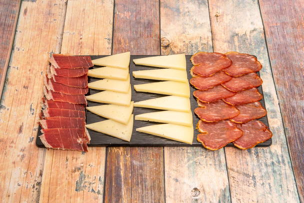 Popular Spanish tapa of Manchego cheese board and Iberian sausages on wooden table - Foto, Imagem
