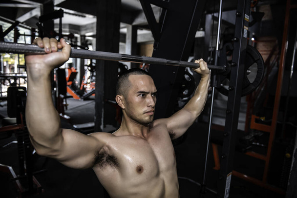 Handsome man working out in the gym, Asian man doing weightlifting to compete in sports,Pull up barbell - Foto, Bild