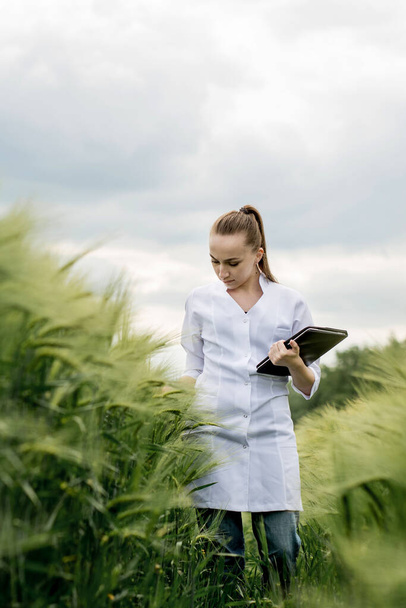 Ecologist in a white coat and glasses examining plants. - Photo, Image