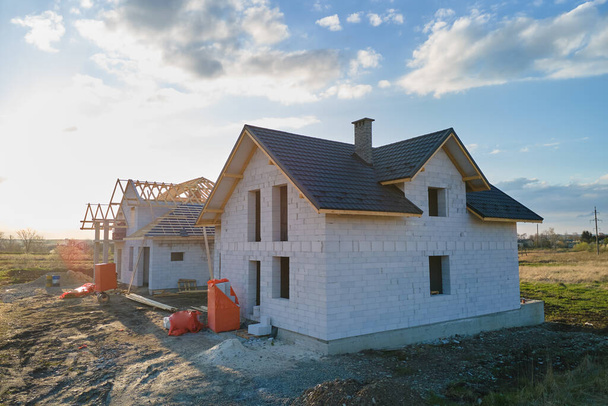 Vista aérea de casa inacabada con paredes de hormigón ligero aireado y marco de techo de madera cubierto con azulejos metálicos en construcción. - Foto, Imagen