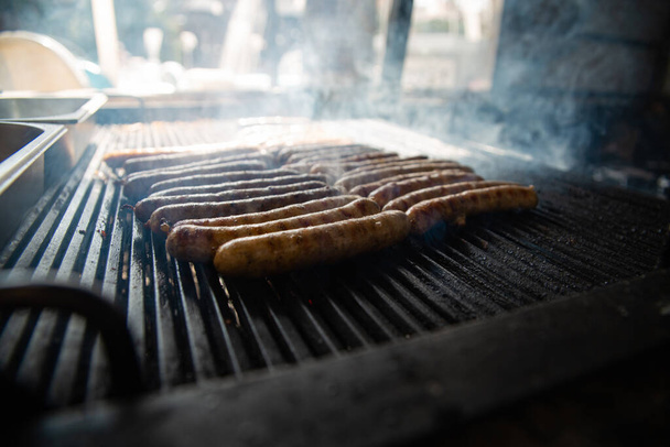 Жареная колбаса на пылающем гриле. Кулинария на углях с дымом - Фото, изображение