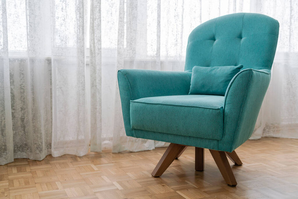 A new and cozy turquoise blue armchair on parquet floor in the living room - Photo, Image