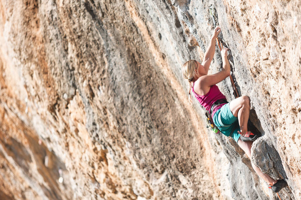 Het meisje klimt op een overhangende rots met een touw. Outdoor sport klimmen. sport en recreatie buitenshuis - Foto, afbeelding
