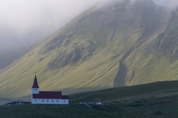 Paisaje de la Iglesia Vik i Myrdal en una colina en el día de verano en Vik - Foto, Imagen