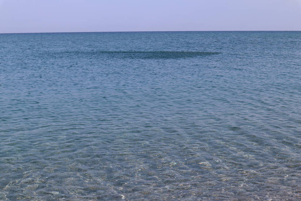 Vista panorâmica da água do mar límpida e uma escola de peixes no horizonte num dia de Verão, Calábria, Itália. Mar transparente azul da paisagem marinha, através da água você pode ver o fundo arenoso, uma escola de peixes no horizonte em um dia ensolarado - Foto, Imagem