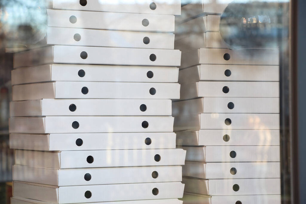 Pizza dağıtım servisinin vitrininde bir sürü beyaz kutuyu bulanıklaştırdı. Yumuşak odak. - Fotoğraf, Görsel