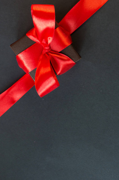 Black Friday - black gift box with a red bow on a dark background. Super sale, sales promotion and special offer. flat lay with place for text. Banner mockup, postcard. - Photo, Image