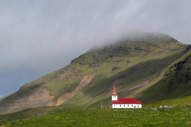 Landscape of Vik i Myrdal church on hill with grassy cliffs in Vik Iceland - Fotoğraf, Görsel