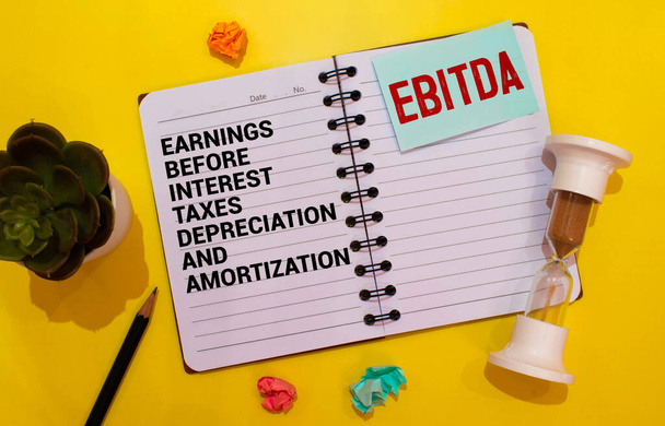Notitieblok met opschriften EBITDA - Verdiensten vóór rente, belastingen, afschrijvingen en afschrijvingen, op een witte kantoorachtergrond. - Foto, afbeelding