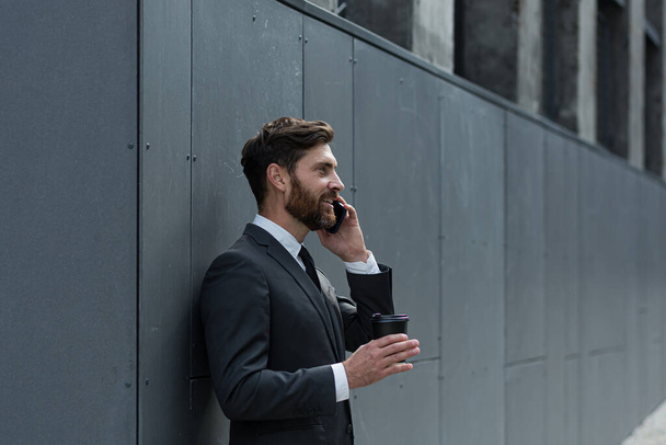 Başarılı iş adamı takım elbiseli bir borsacı dışarıda ofisin yanında telefonla konuşuyor, bankacı öğle arasında elinde bir fincan kahveyle gülümsüyor. - Fotoğraf, Görsel