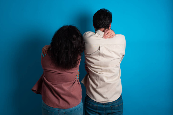 young couple expecting a baby standing against blue background hugging herself happy and positive from backwards. Self love and self care - Photo, Image