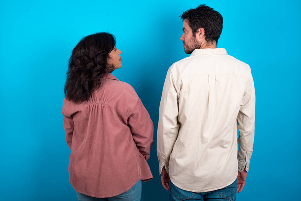 The back side view of a young couple expecting a baby standing against blue background . Studio Shoot. - Fotografie, Obrázek