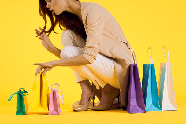 cheerful woman with multicolored bags posing yellow background - 写真・画像