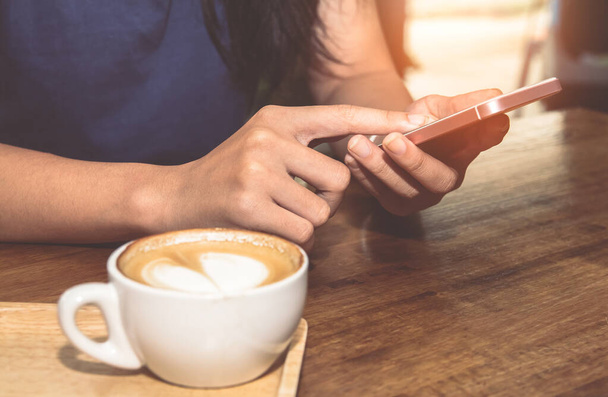 Close-up van de vrouw handen houden aanraken mobiele telefoon met lege kopieerruimte voor uw sms-bericht in cafe met licht zonsondergang, Vintage tone.Selective focus - Foto, afbeelding
