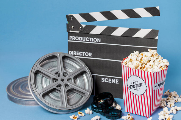 film reels film strips clapperboard with popcorn box blue background. High quality photo - Fotoğraf, Görsel