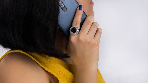 Латинская женщина отвечает на звонок, показывая красивое серебряное кольцо с фиолетовым камнем. - Фото, изображение