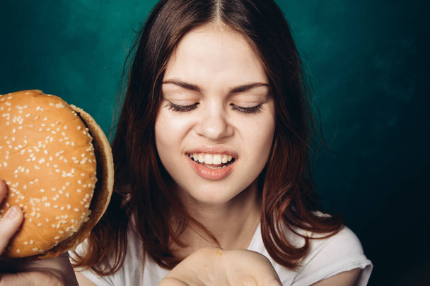 woman eating hamburger fast food snack close-up - 写真・画像