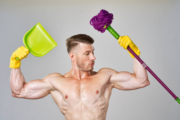 a man in yellow gloves with a naked torso a mop in his hands cleaning - 写真・画像
