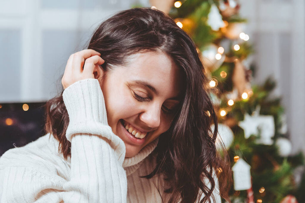 nő fehér pulóver pózol közel karácsonyfa portré - Fotó, kép