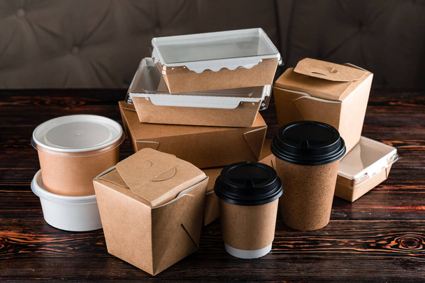 set eco tableware for food delivery craft. Eco craft paper tableware. Paper cups, dishes, bag, fast food containers, box for delivery food on wooden background. Recycling concept. Zero waste, plastic-free and eco-friendly living - Photo, Image