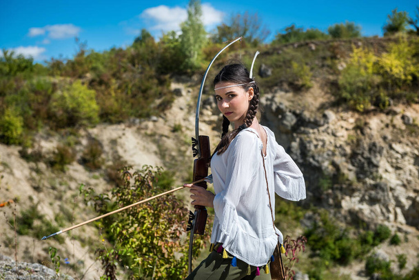 弓と矢を持ったアメリカの先住民としてのスタイルの若い女性は - 写真・画像