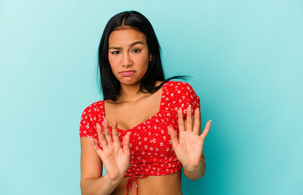 Young Venezuelan woman isolated on blue background rejecting someone showing a gesture of disgust. - Photo, Image