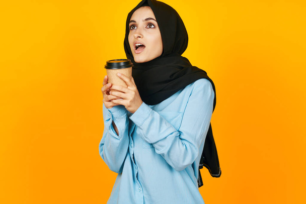 cheerful woman a glass of coffee a warming drink yellow background - Fotó, kép