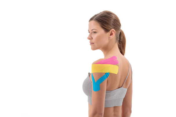 Portrait of woman with therapeutic tape for shoulder pain, aches and tension. It is also used for prevention and treatment in competitive sports. - Foto, immagini