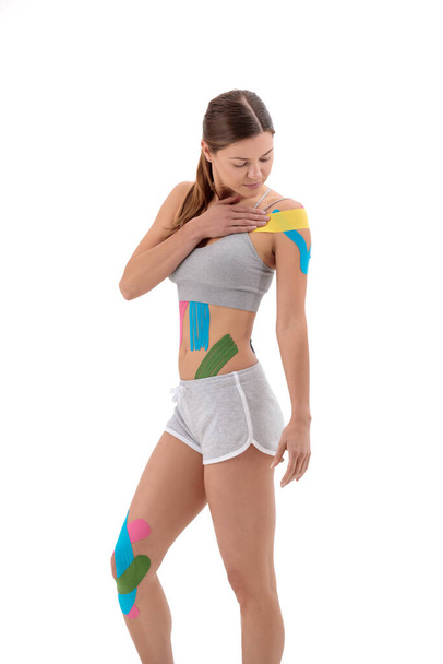 Beyaz tenli genç bir atletik kadının vücuduna uygulanan fizik bantları. Fizyoterapi, kinesio bantlama, kineziyoloji ve iyileşme tedavi kavramları. - Fotoğraf, Görsel