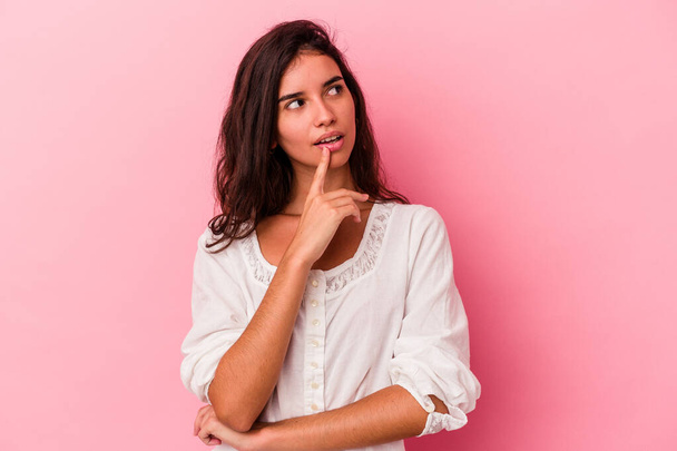 Young caucasian woman isolated on pink background looking sideways with doubtful and skeptical expression. - Foto, Imagem