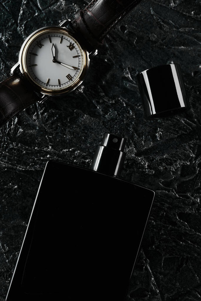 Mens watches and an open bottle of black eau de toilette lie on a dark textured background. Fragrance for men. - Valokuva, kuva
