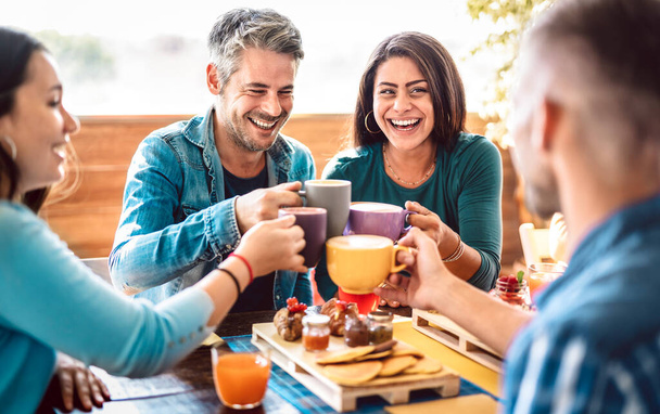Emberek csoport pohárköszöntő latte a kávézó tetőn - Baráti beszélgetés és szórakozás együtt cappuccino étterem - Életstílus koncepció boldog férfiak és nők a kávézó teraszán - Bright meleg szűrő - Fotó, kép