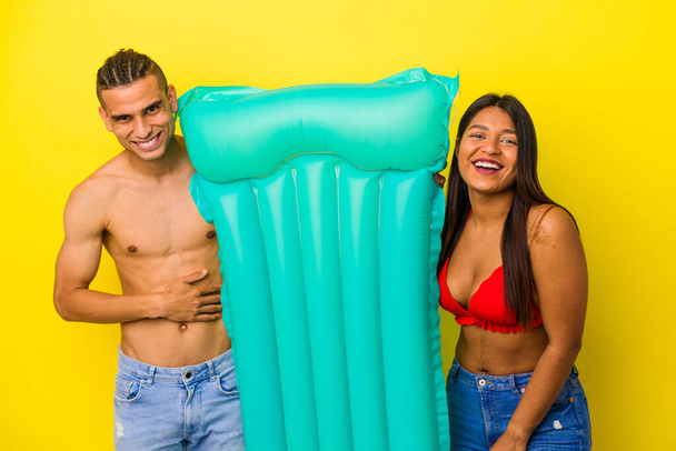 Nuori latino pari tilalla ilmapatja eristetty keltainen tausta nauraa ja hauskaa. - Valokuva, kuva