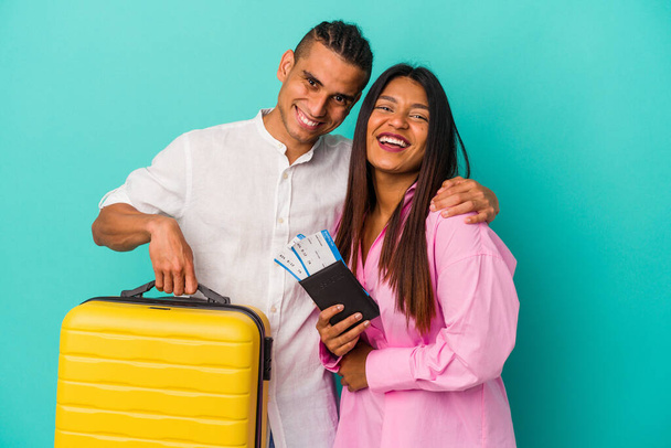 若いラテン系のカップルは青の背景で孤立した旅行に行く笑いと楽しみを持って. - 写真・画像