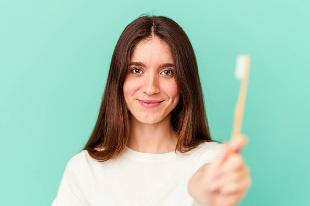 Young caucasian woman holding a toothbrush isolated on blue background - Photo, Image